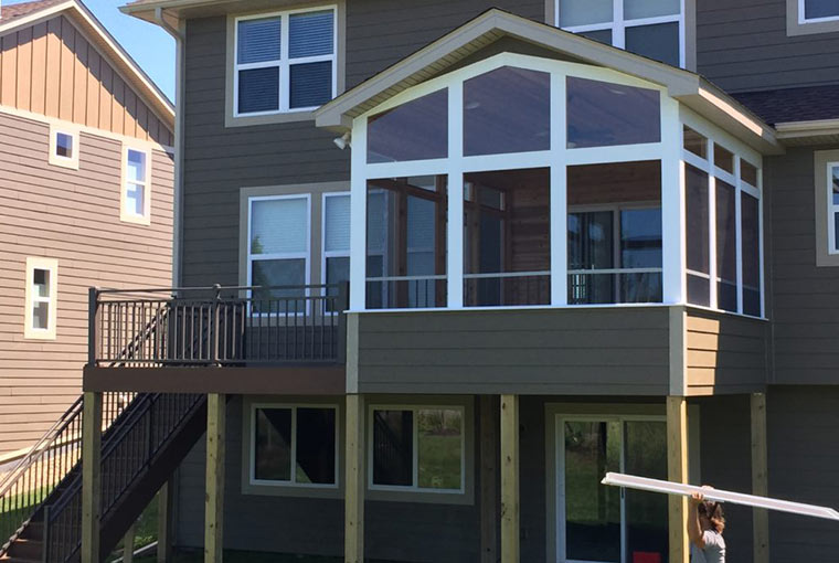 A beautiful screen porch attached to a contemporary home in the same style, flanked by a maintenance free deck in Chaska, MN